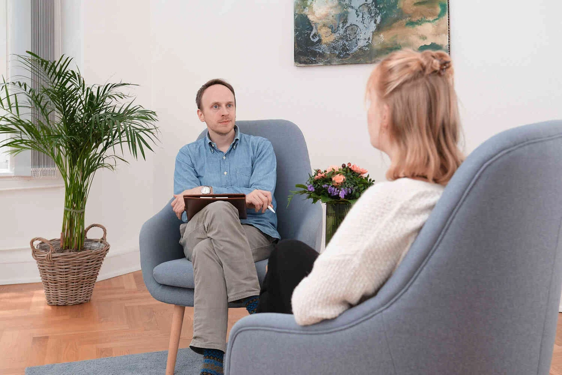 Mann mit Klemmbrett sitzt einer Frau in einem Gespr&auml;ch gegen&uuml;ber