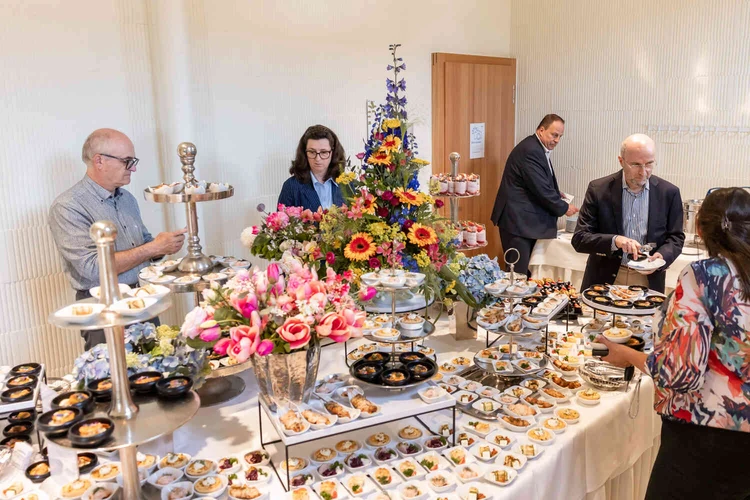 Buffet mit Speisen, Blumen und G&auml;sten bei der Er&ouml;ffnungsfeier