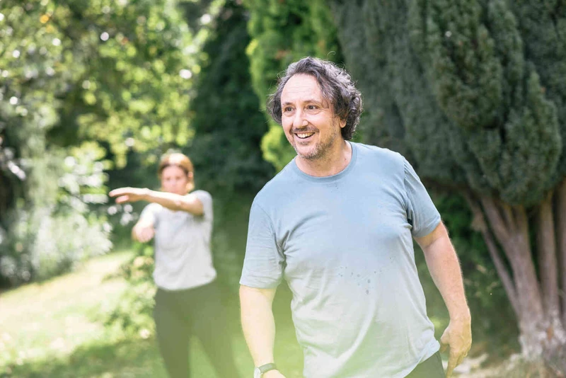 Zwei Personen machen Bewegungs&uuml;bungen im Gr&uuml;nen