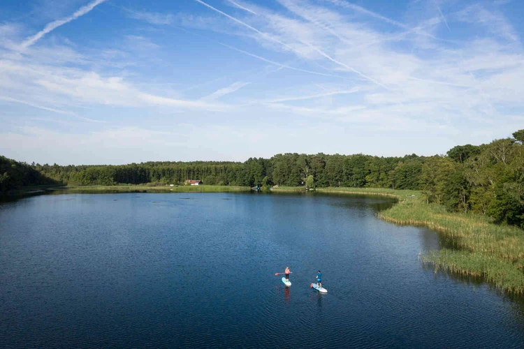 See mit Wald und zwei Personen auf dem Wasser