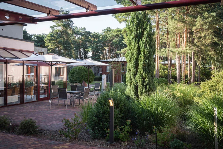 Terrasse eines Geb&auml;udes mit Garten und angrenzendem Wald