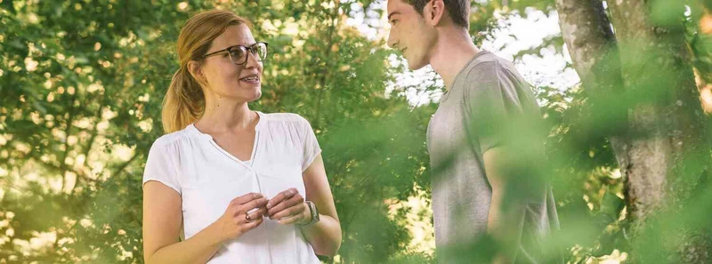 Frau und junger Mann sprechen im Gr&uuml;nen miteinander