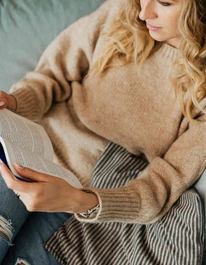Person h&auml;lt ein Buch auf dem Scho&szlig; und liest