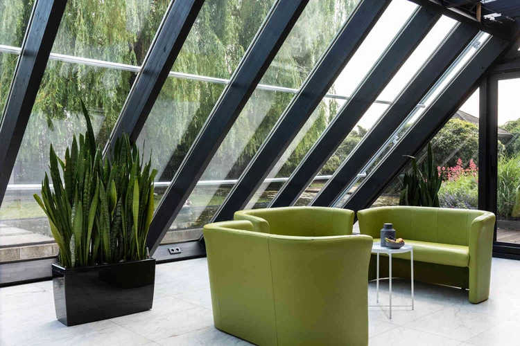 Sitzbereich mit gr&uuml;nen Sofas und Glasdach