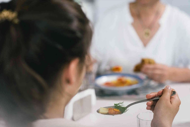 Personen sitzen gemeinsam beim Essen am Tisch