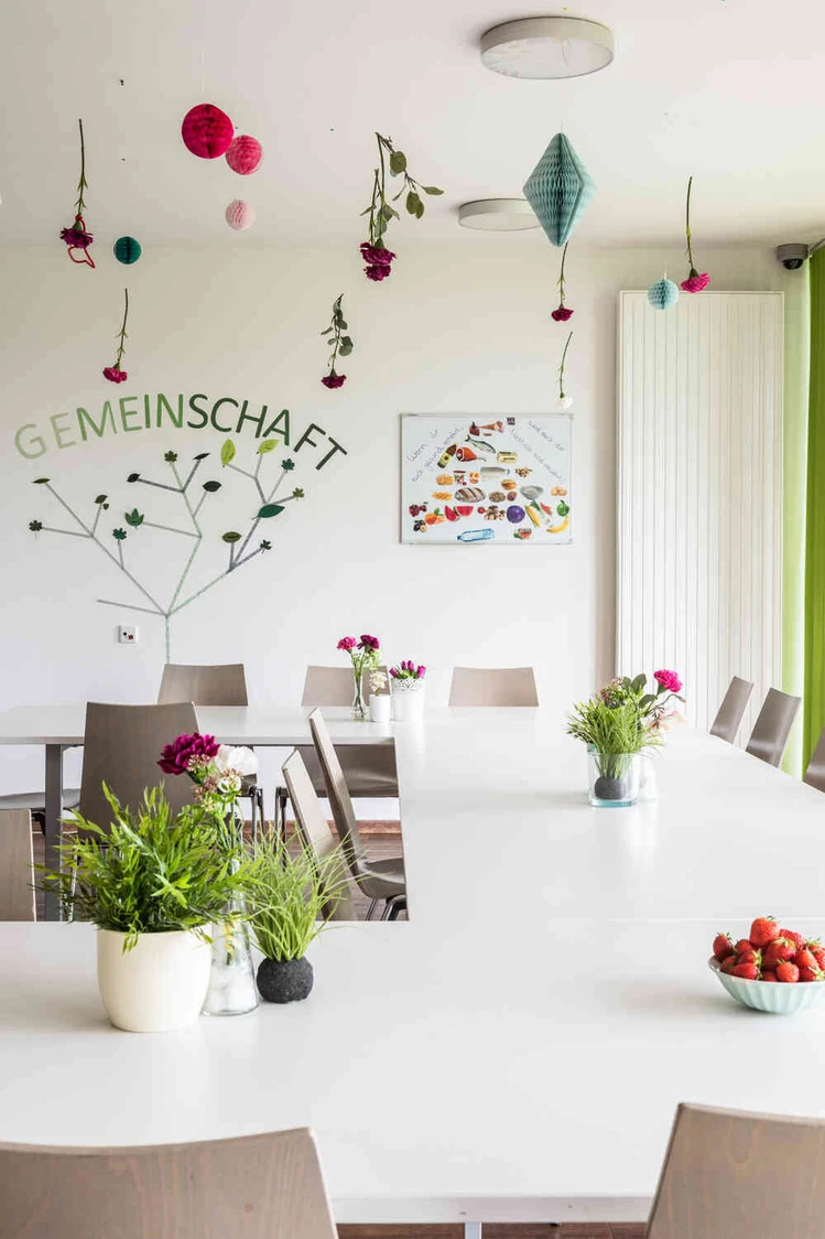 Heller Raum mit bunter Wandgestaltung und Blumen auf den Tischen