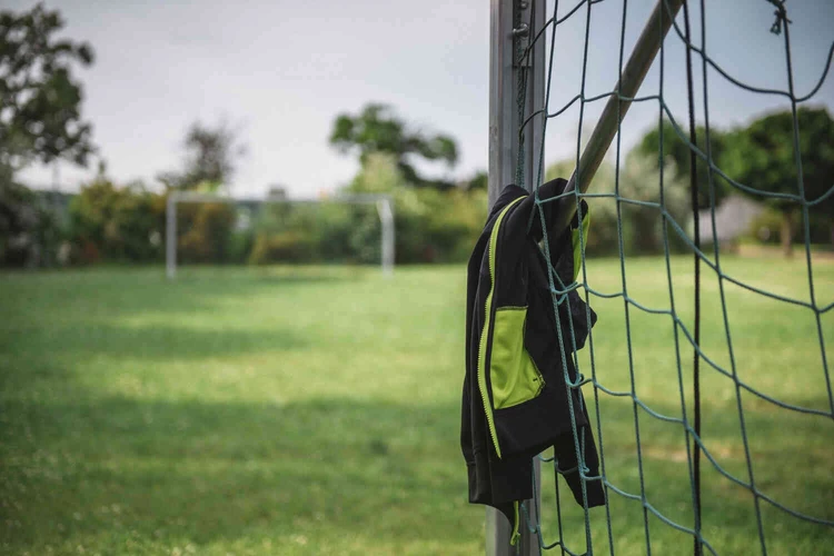 Sportjacke h&auml;ngt an einem Fu&szlig;balltor im Gr&uuml;nen