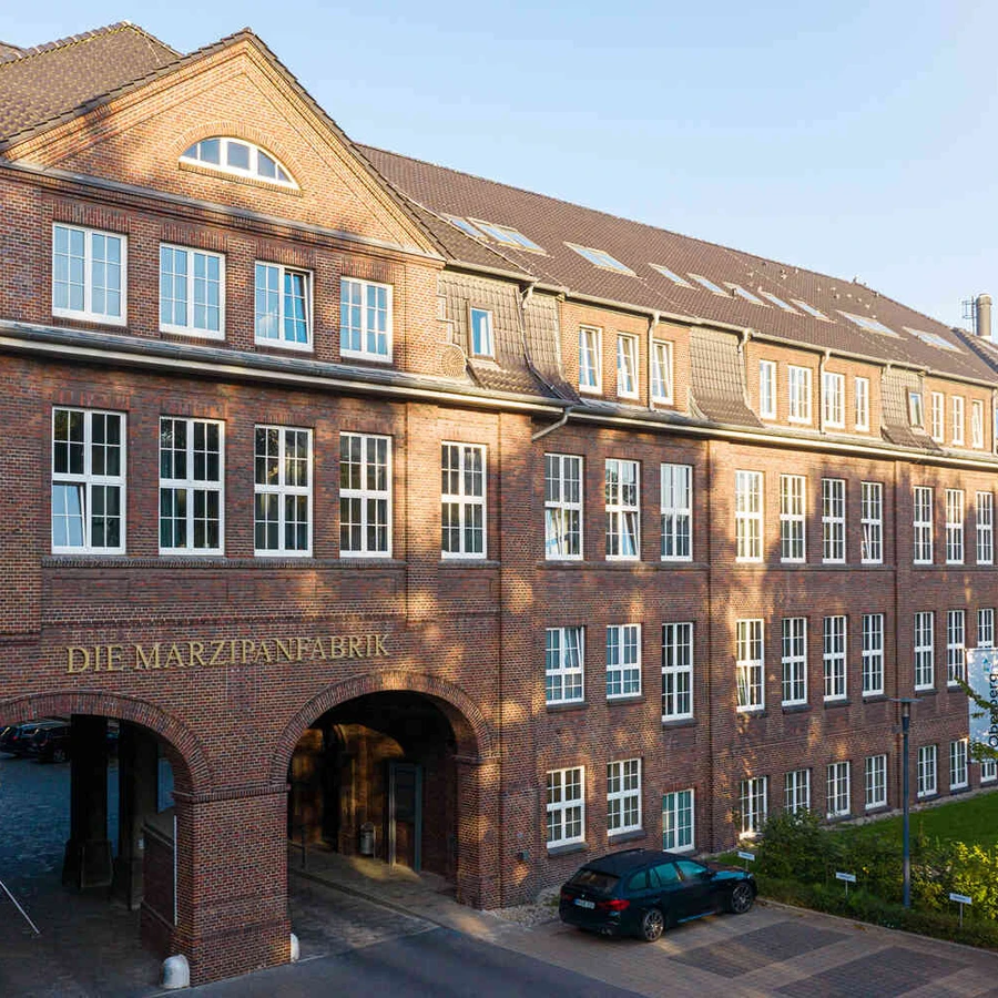 Historisches Backsteingeb&auml;ude der Oberberg Fachklinik Marzipanfabrik mit Torbogen und Innenhofzufahrt bei Tageslicht.