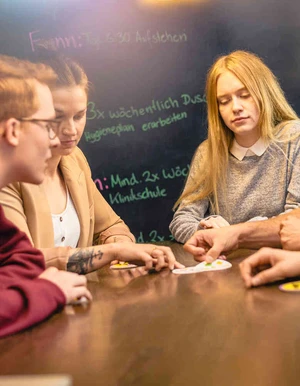 Junge Personen sitzen gemeinsam an einem Tisch