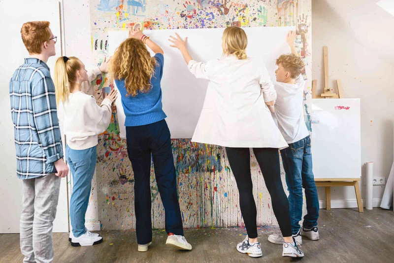 Gruppe arbeitet gemeinsam an einem Plakat an bunter Wand