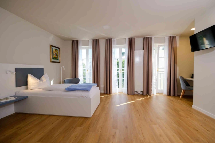 Helles Patientenzimmer der Oberberg Fachklinik Potsdam mit Bett und Balkonfenster