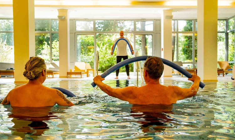 Zwei Personen machen eine &Uuml;bung im Schwimmbad