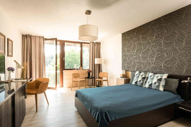Helles Patientenzimmer mit Bett und Sitzecke