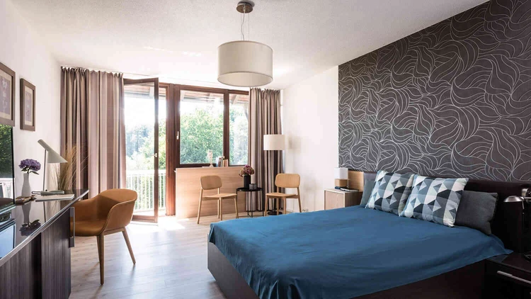 Helles Patientenzimmer mit Bett und Balkonfenster