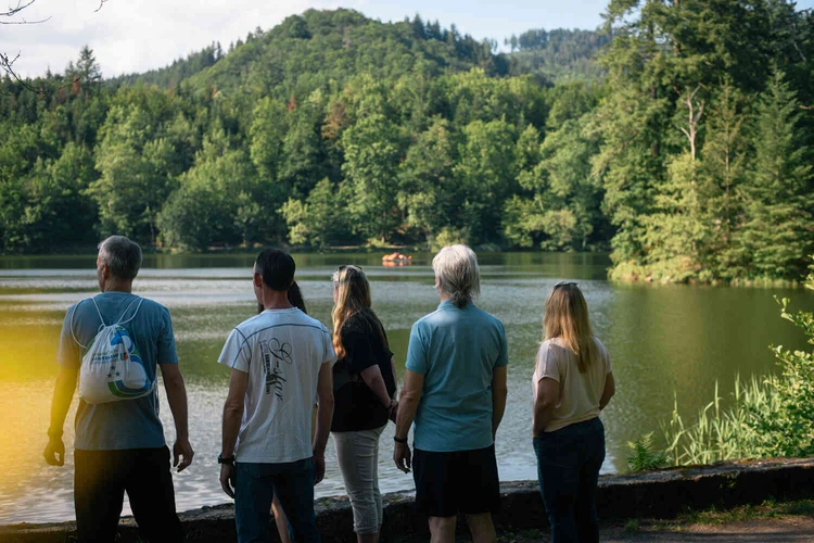 Gruppe steht am Seeufer mit Blick auf die Landschaft