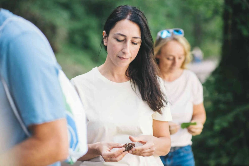 Personen stehen im Gr&uuml;nen und sp&uuml;ren Naturmaterialien