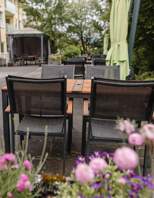 Terrasse mit Tischen und Sonnenschirmen in einer gr&uuml;nen Au&szlig;enanlage