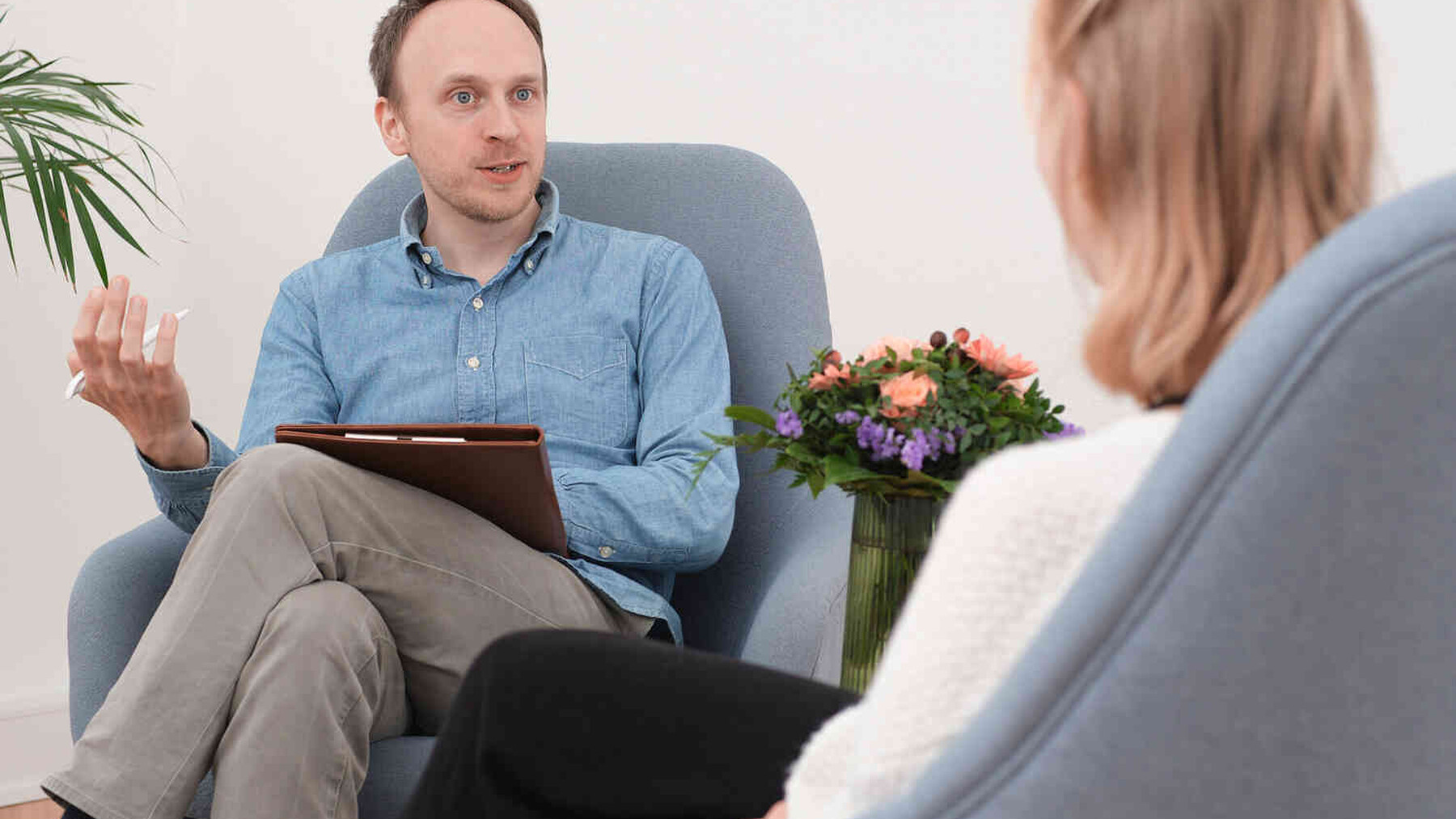 Mann mit Klemmbrett sitzt einer Frau in einem Beratungsgespr&auml;ch gegen&uuml;ber