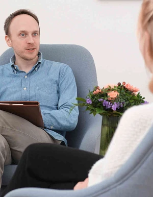 Mann mit Klemmbrett sitzt einer Frau in einem Beratungsgespr&auml;ch gegen&uuml;ber
