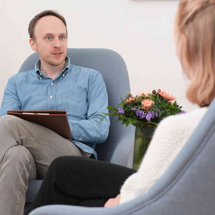 Mann mit Klemmbrett sitzt einer Frau in einem Beratungsgespr&auml;ch gegen&uuml;ber