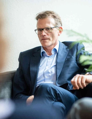 Mann sitzt in einem Sessel in einem hellen Raum