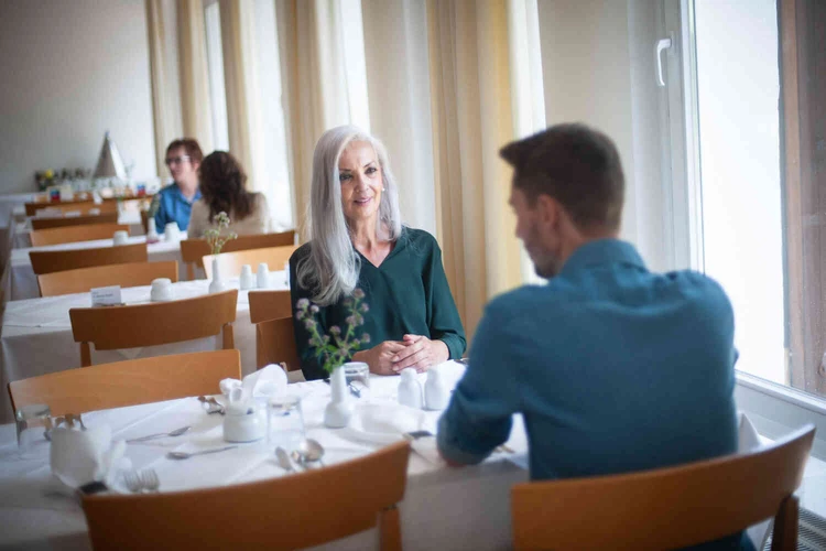 Personen sitzen an einem gedeckten Tisch in einem hellen Raum