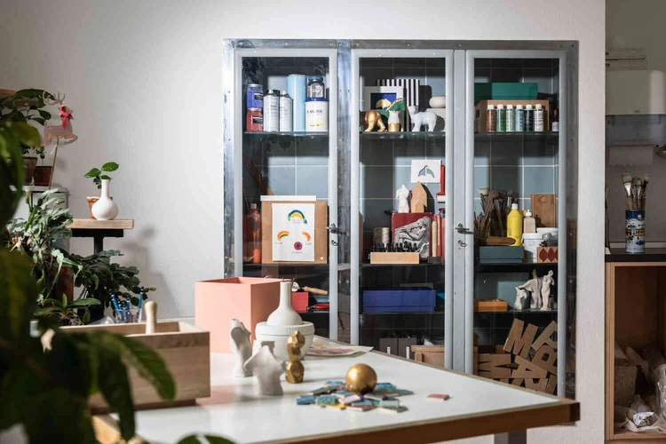 Schrank mit Farben, Pinseln und Werkmaterialien in einem hellen Atelierraum