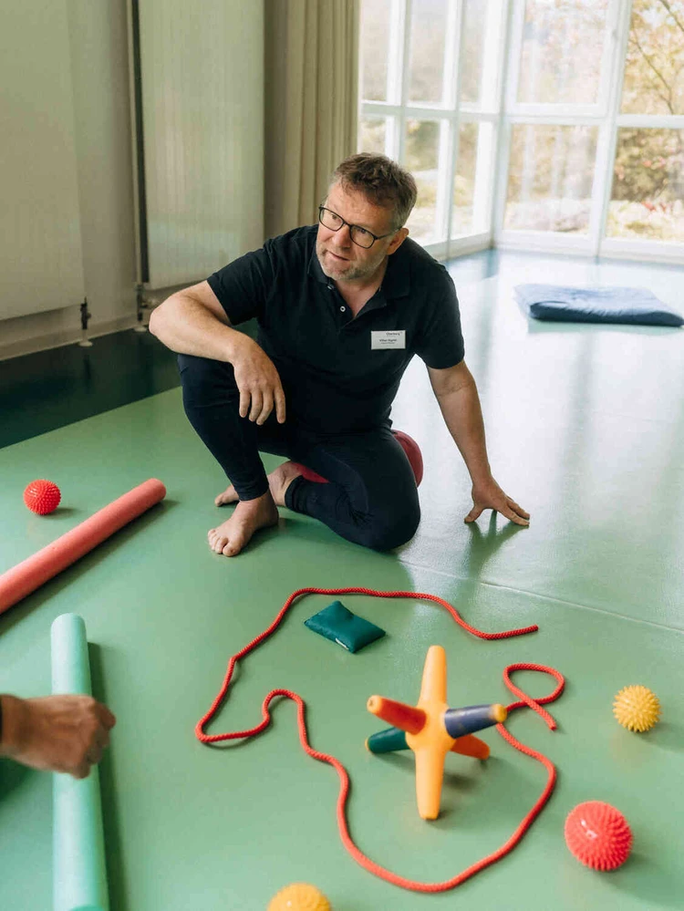 Person sitzt auf dem Boden bei einer &Uuml;bung mit verschiedenen Sportaccessiores