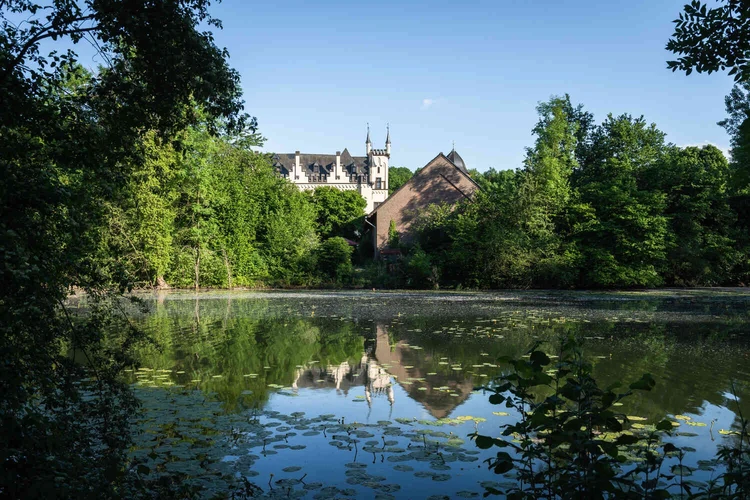 Blick &uuml;ber einen See auf das Wasserschl&ouml;sschen im Gr&uuml;nen