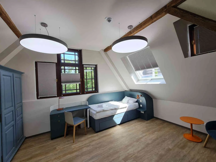 Patientenzimmer mit Bett, Tisch und Fenster