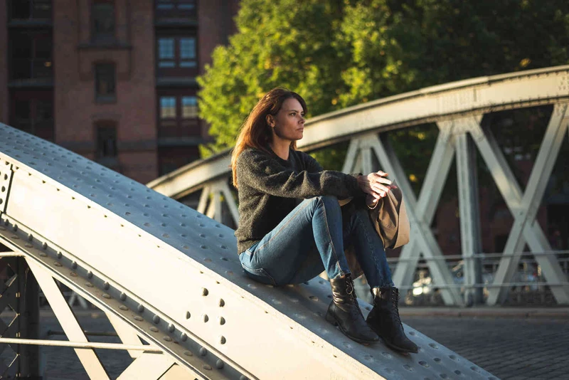Frau sitzt auf einer Stahlkonstruktion einer Br&uuml;cke