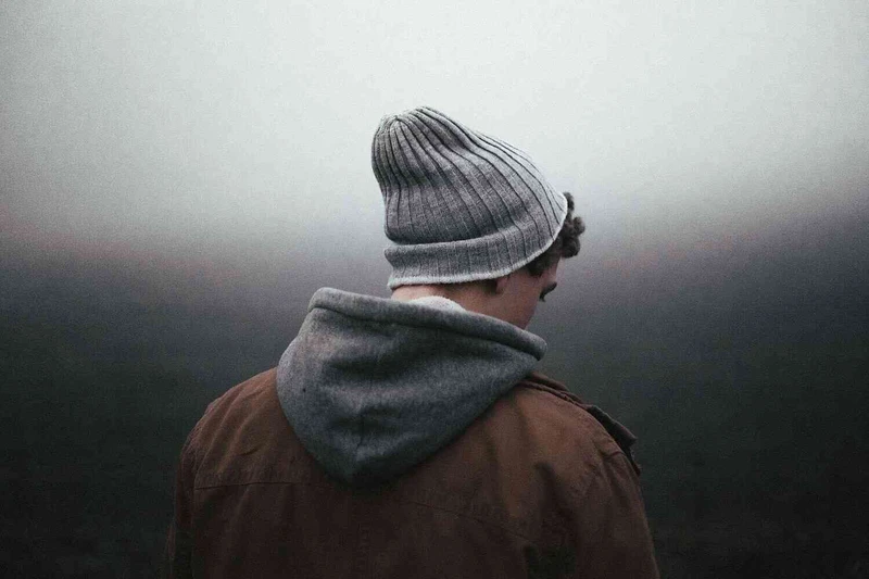 Junger Mann steht mit R&uuml;cken zur Kamera mit dunklen hintergrund