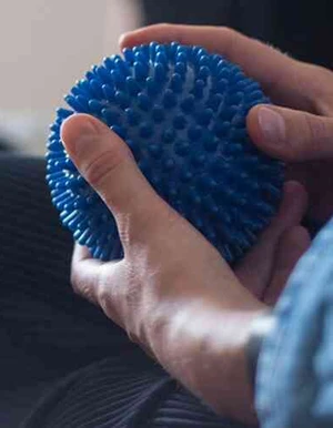 Person h&auml;lt einen blauen Igelball w&auml;hrend eines Gespr&auml;chs