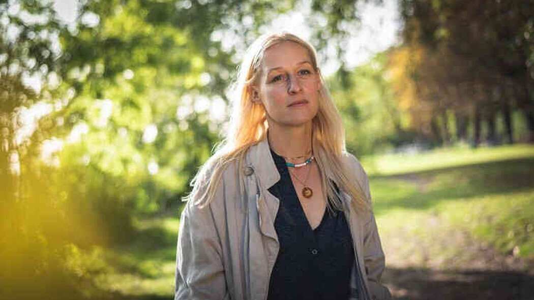 Blonde Frau steht nachdenklich auf einem Weg im Gr&uuml;nen