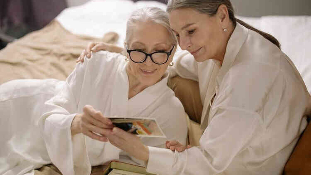 Zwei Frauen betrachten gemeinsam ein Foto im Bett
