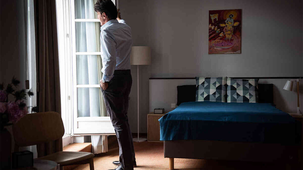Mann steht nachdenklich am Fenster in einem Zimmer