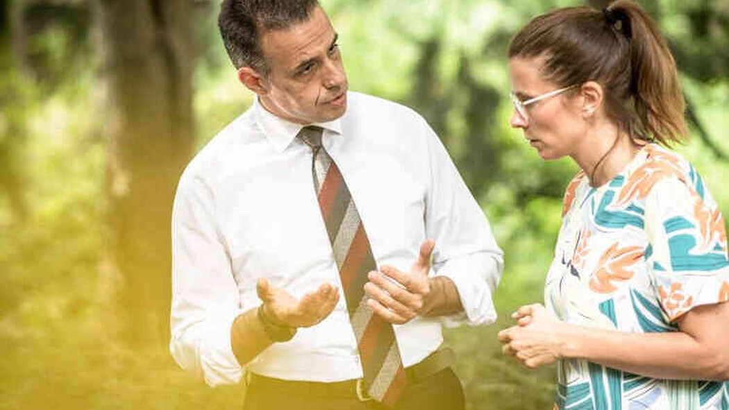 Mann erkl&auml;rt einer Frau etwas im Gespr&auml;ch im Gr&uuml;nen