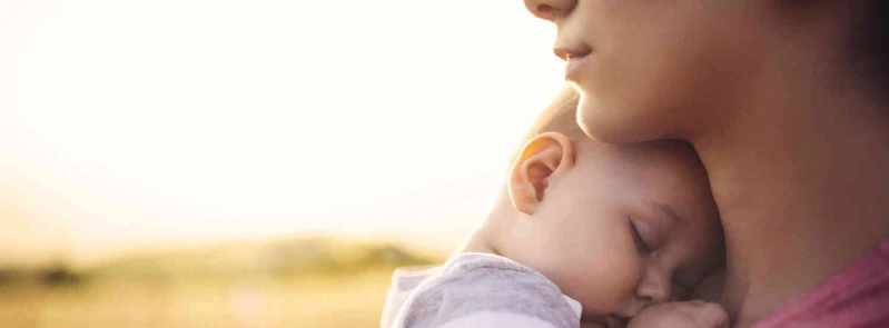 Nahaufnahme eines schlafenden Babys an der Schulter einer erwachsenen Person